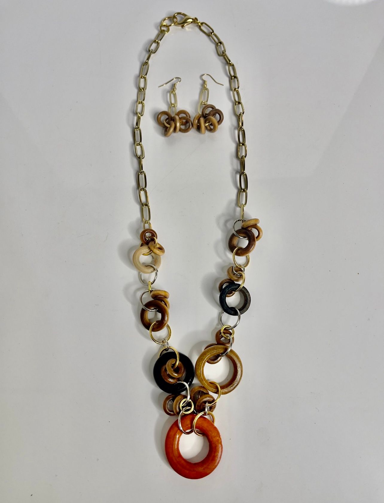 Gold necklace with wooden rings, and matching earrings. Orange, brown, and beige colors.