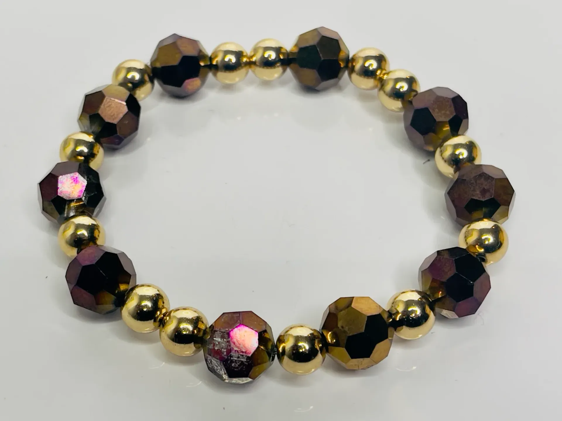 Gold and iridescent bead bracelet on a white surface.
