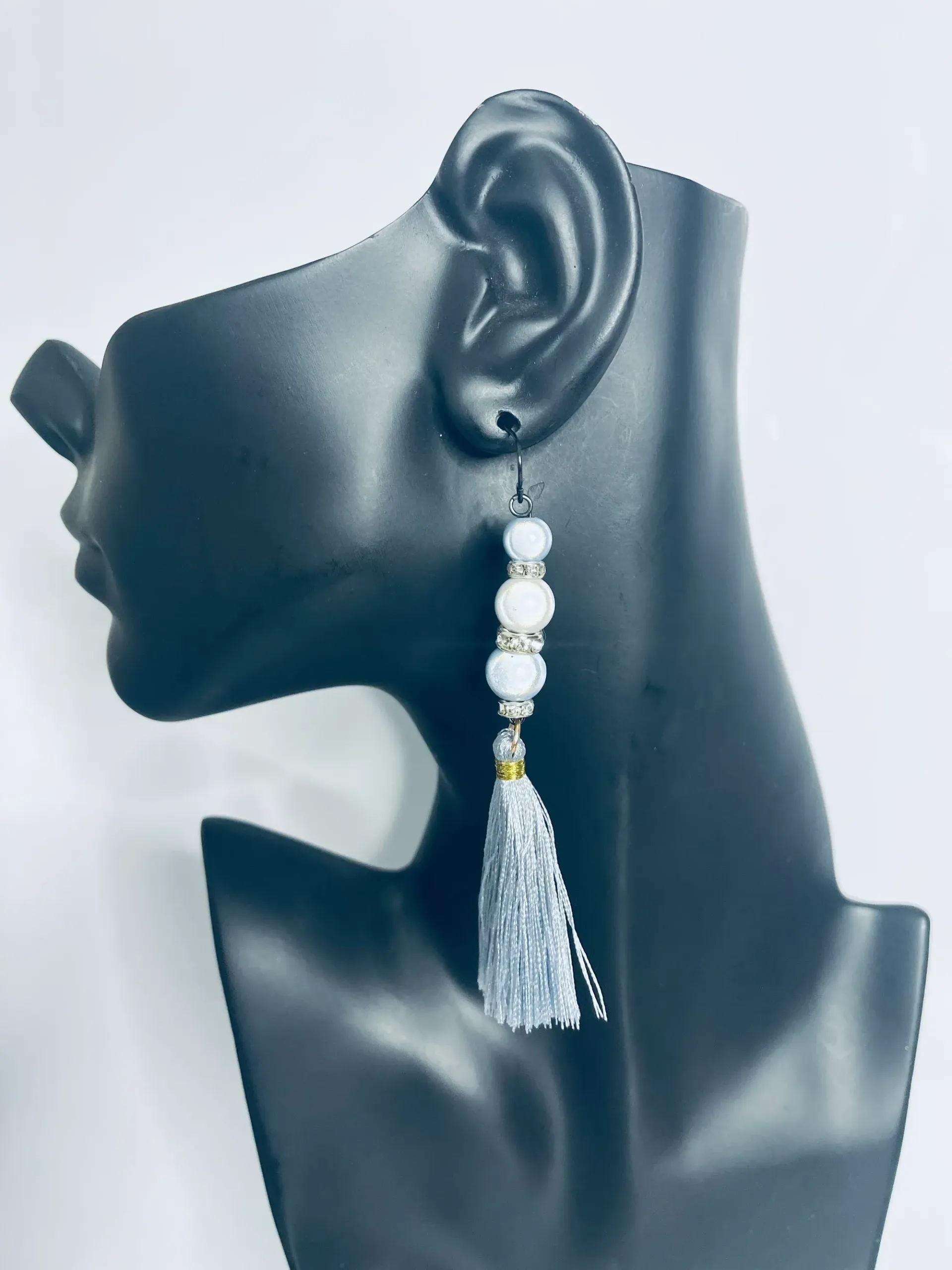 Grey beaded tassel earrings on a black mannequin ear.