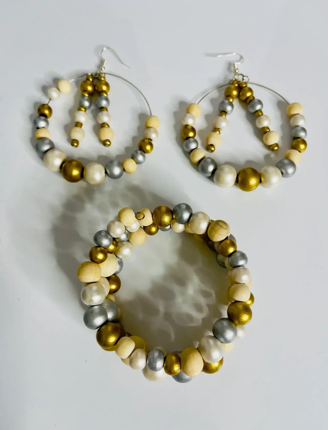 Beaded jewelry set: hoop earrings and bracelet with gold, silver, and cream-colored beads.