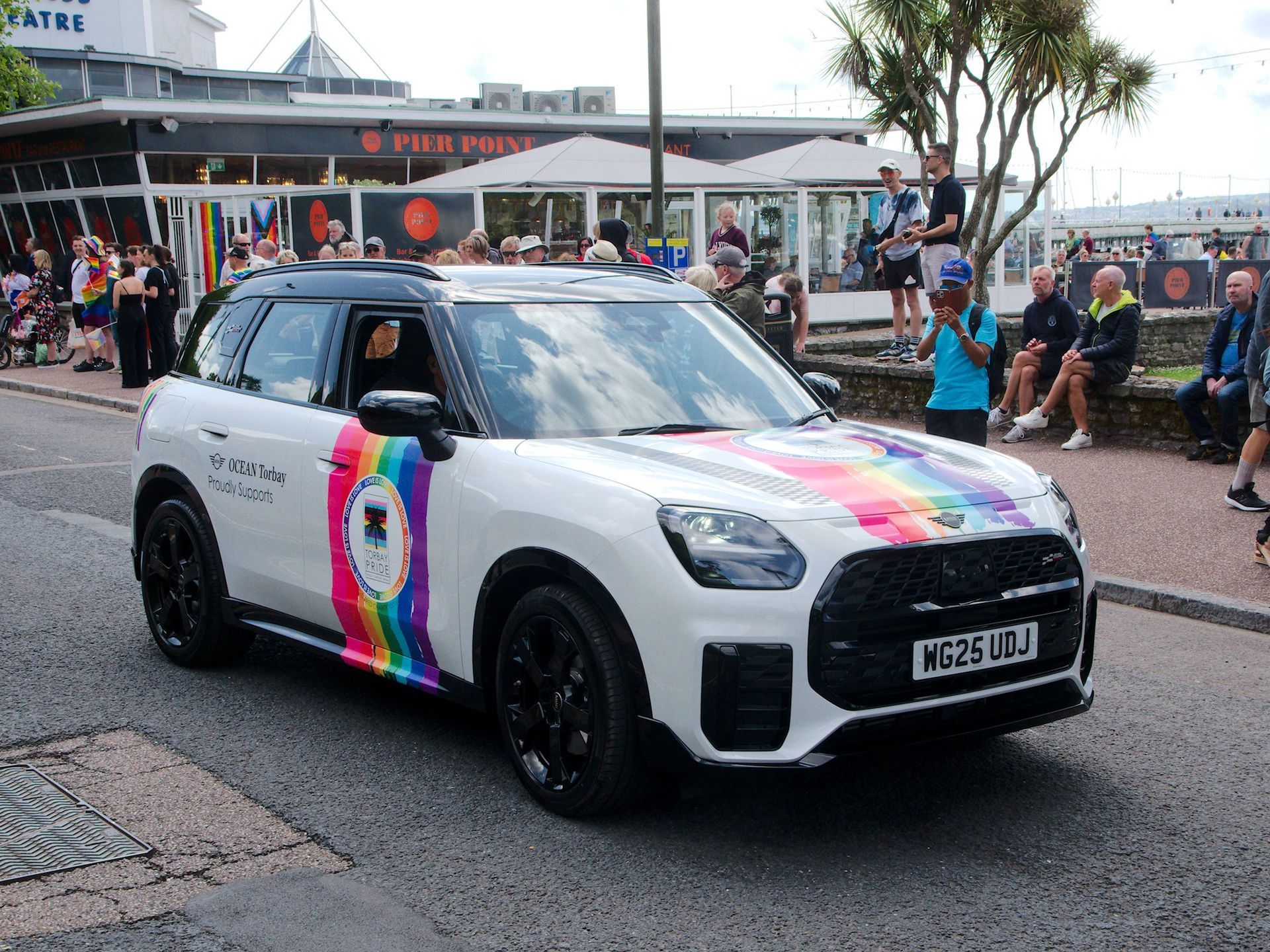 A white mini with Torbay Pride logo and Pride colours
