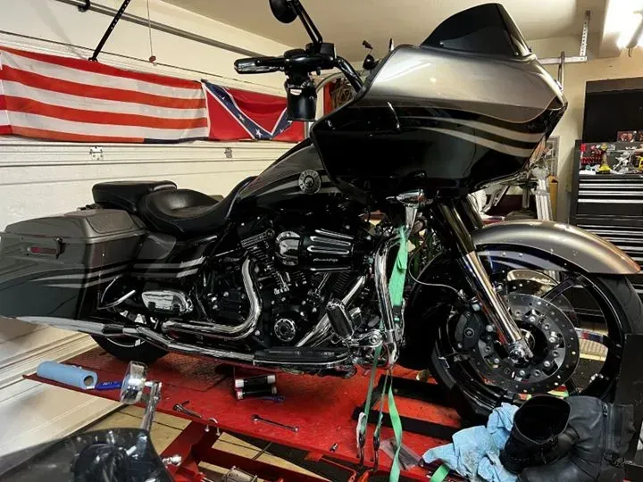 A harley davidson motorcycle is sitting on a lift in a garage.