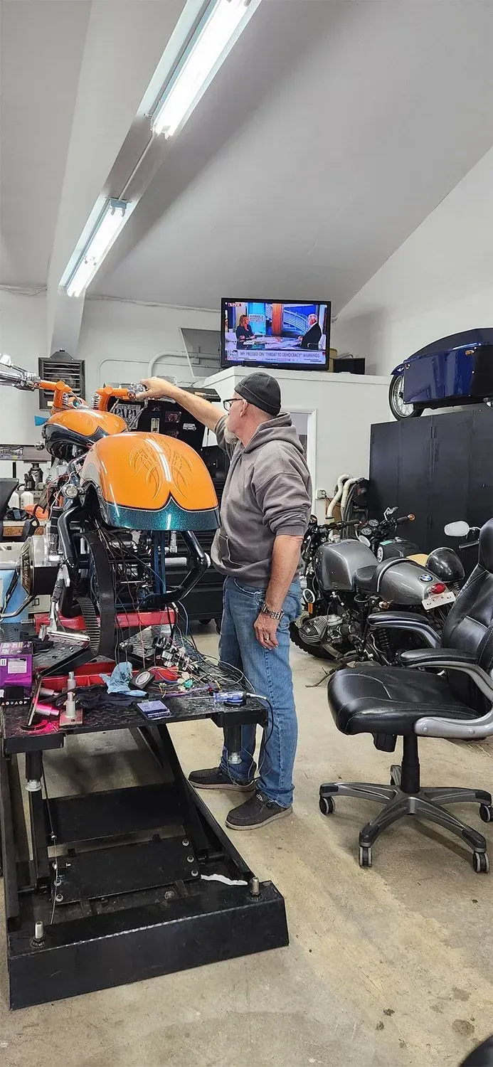 A man is working on a motorcycle in a garage.