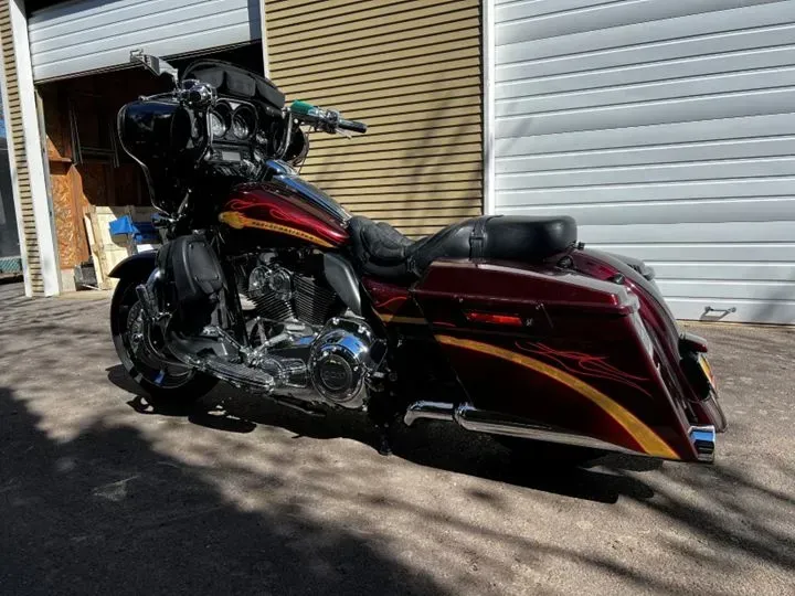 A red harley davidson motorcycle is parked in front of a garage door.