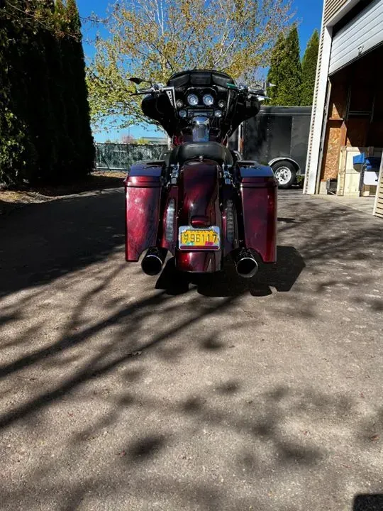 A red motorcycle is parked in a driveway next to a garage.