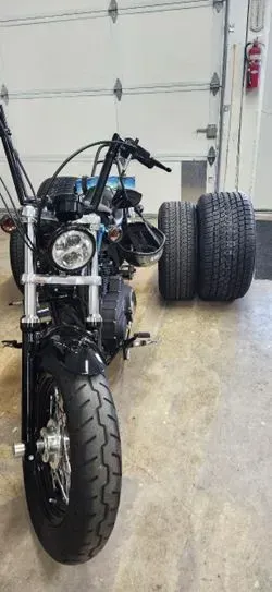 A motorcycle is parked in a garage next to two tires.