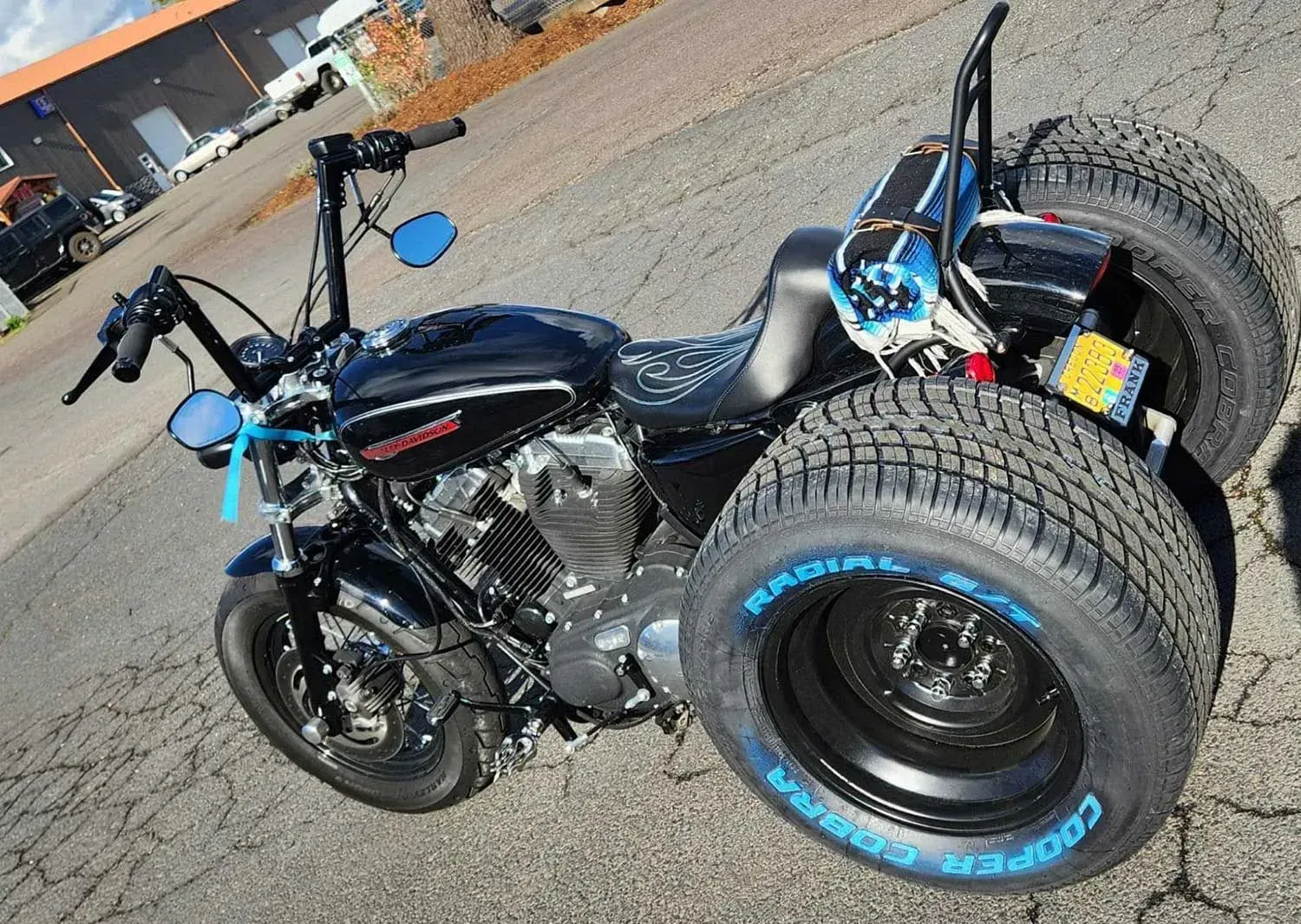 A motorcycle with three tires on it is parked on the side of the road.