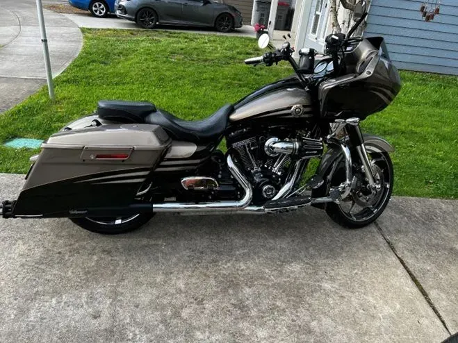 A harley davidson motorcycle is parked on the sidewalk in front of a house.