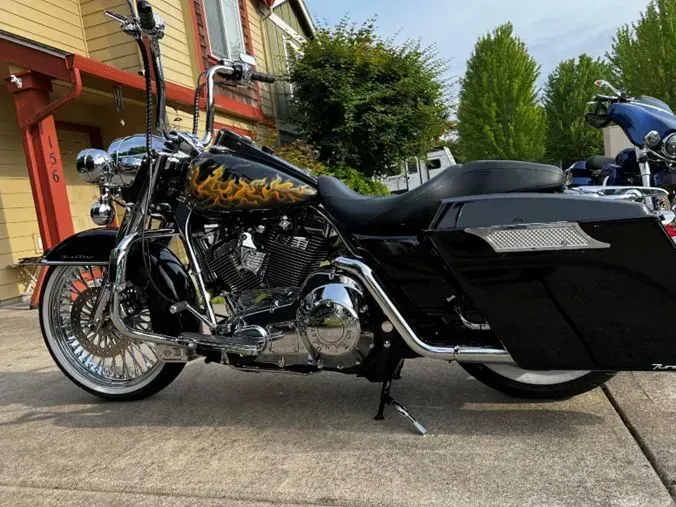 A black harley davidson motorcycle is parked on the sidewalk in front of a house.