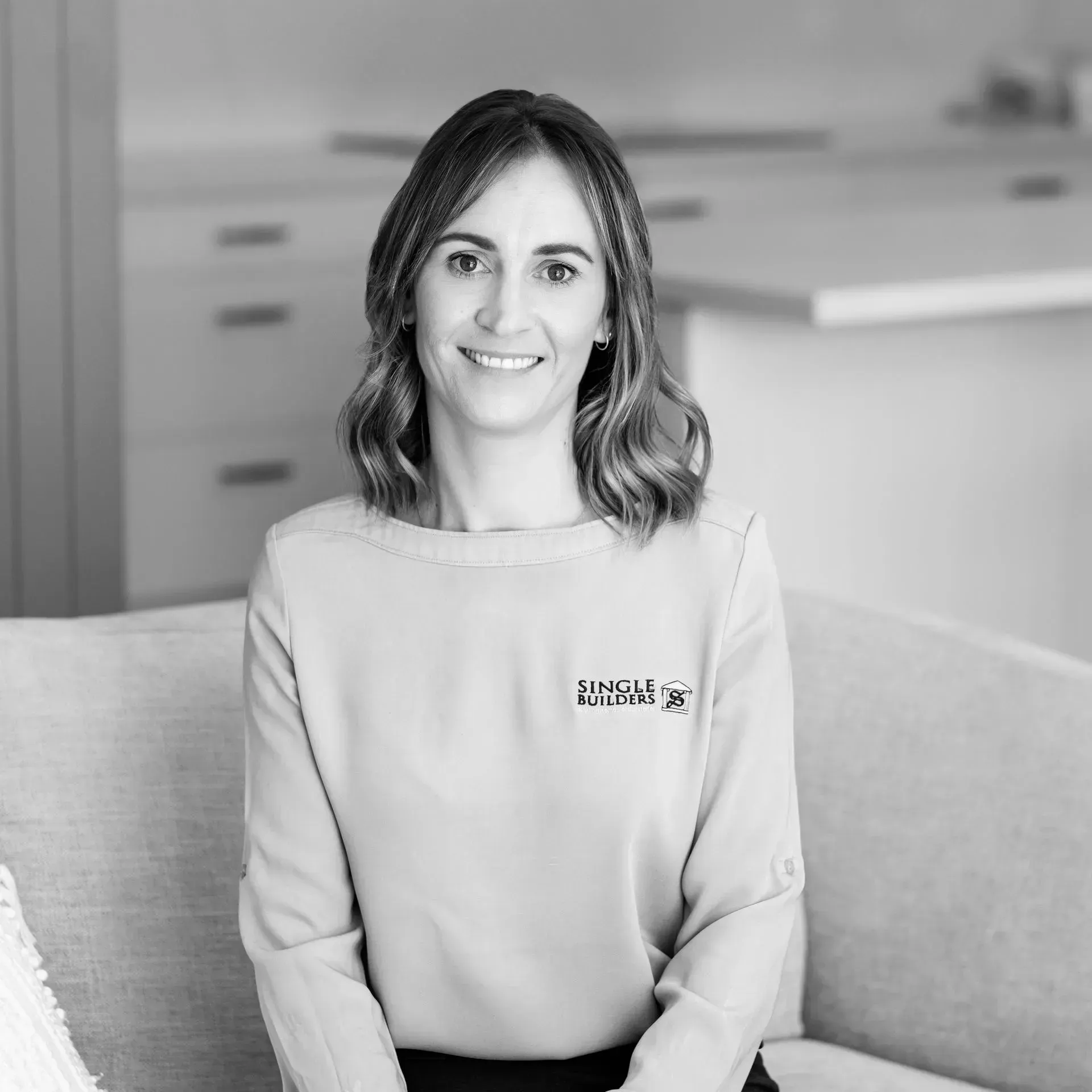 A woman is sitting on a couch in a black and white photo.