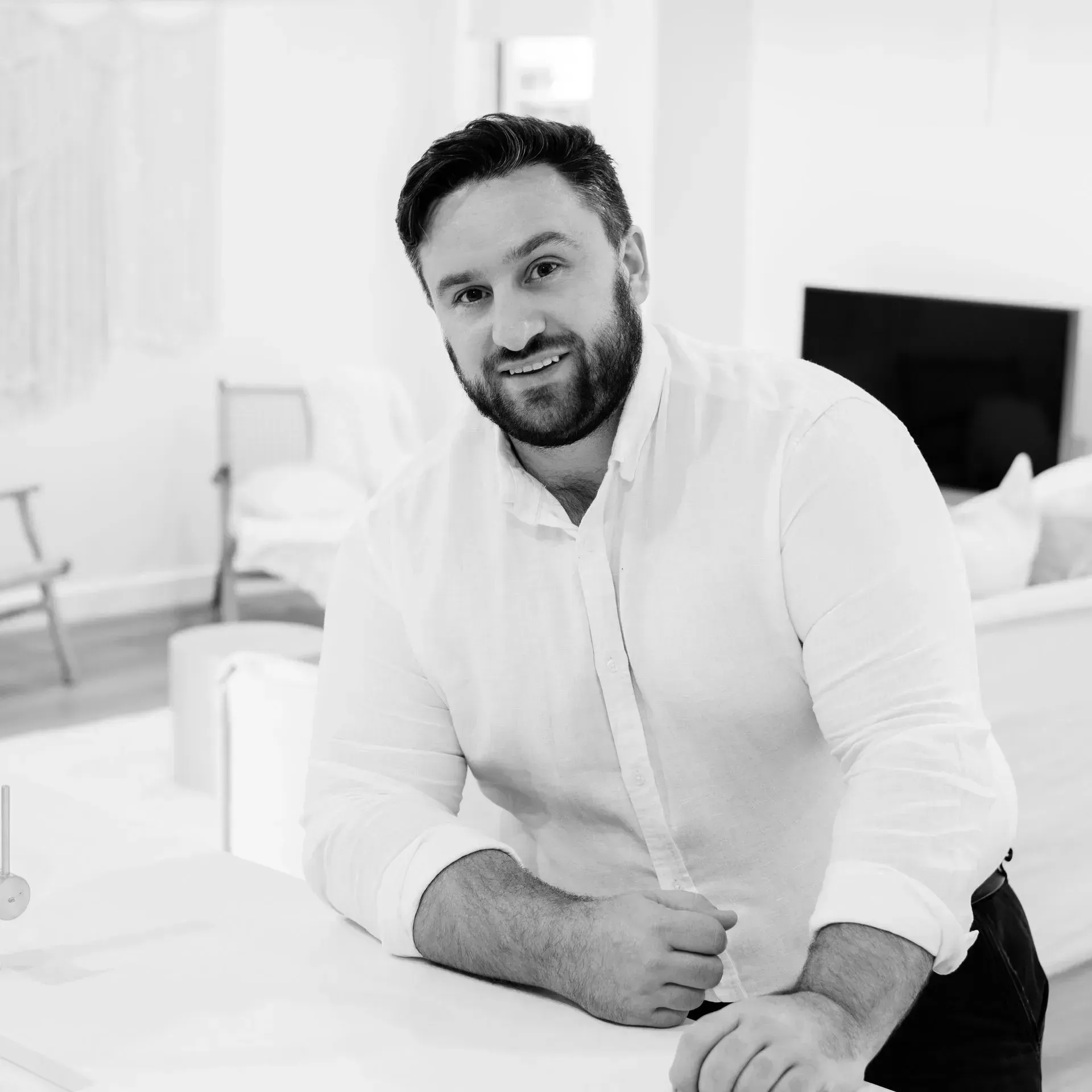 A man with a beard is sitting at a table in a living room.