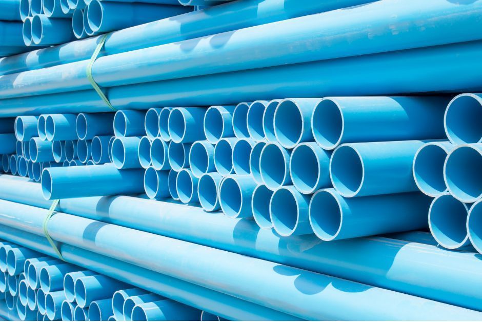 A large stack of light blue PVC pipes neatly piled in rows.