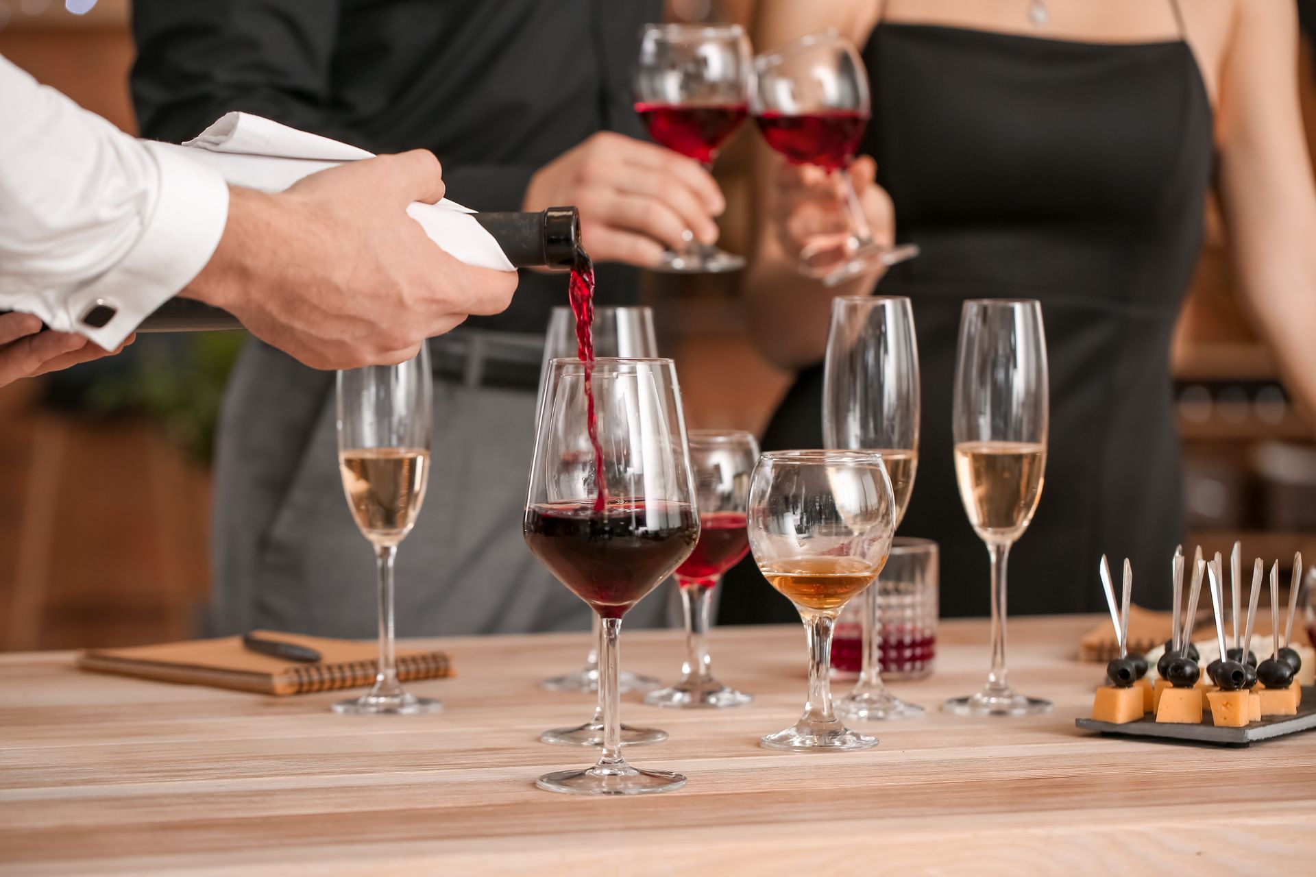 A man is pouring wine into a glass at a party.
