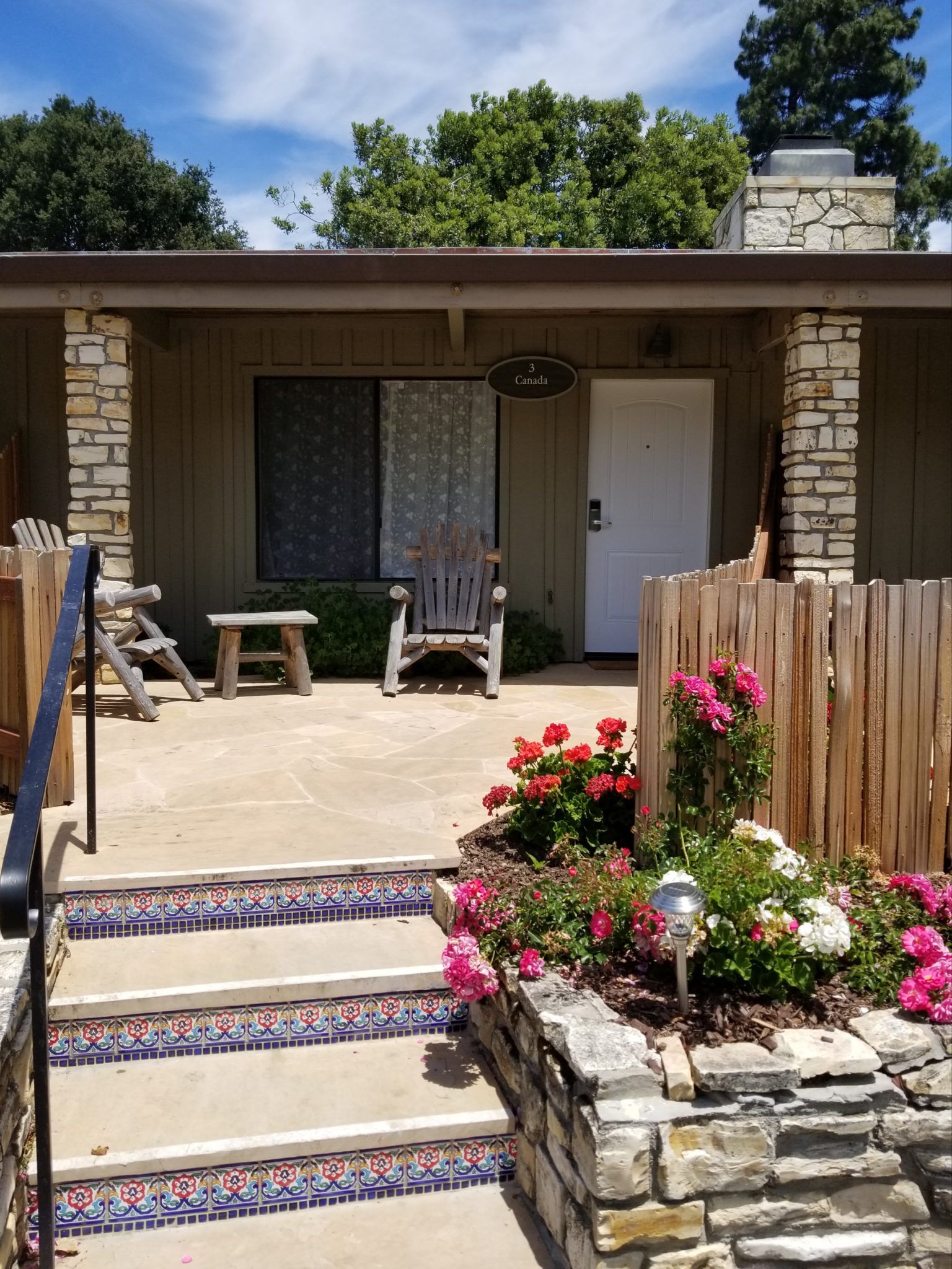 Guest room entrance with concrete steps, blooming colorful flowers and two chairs