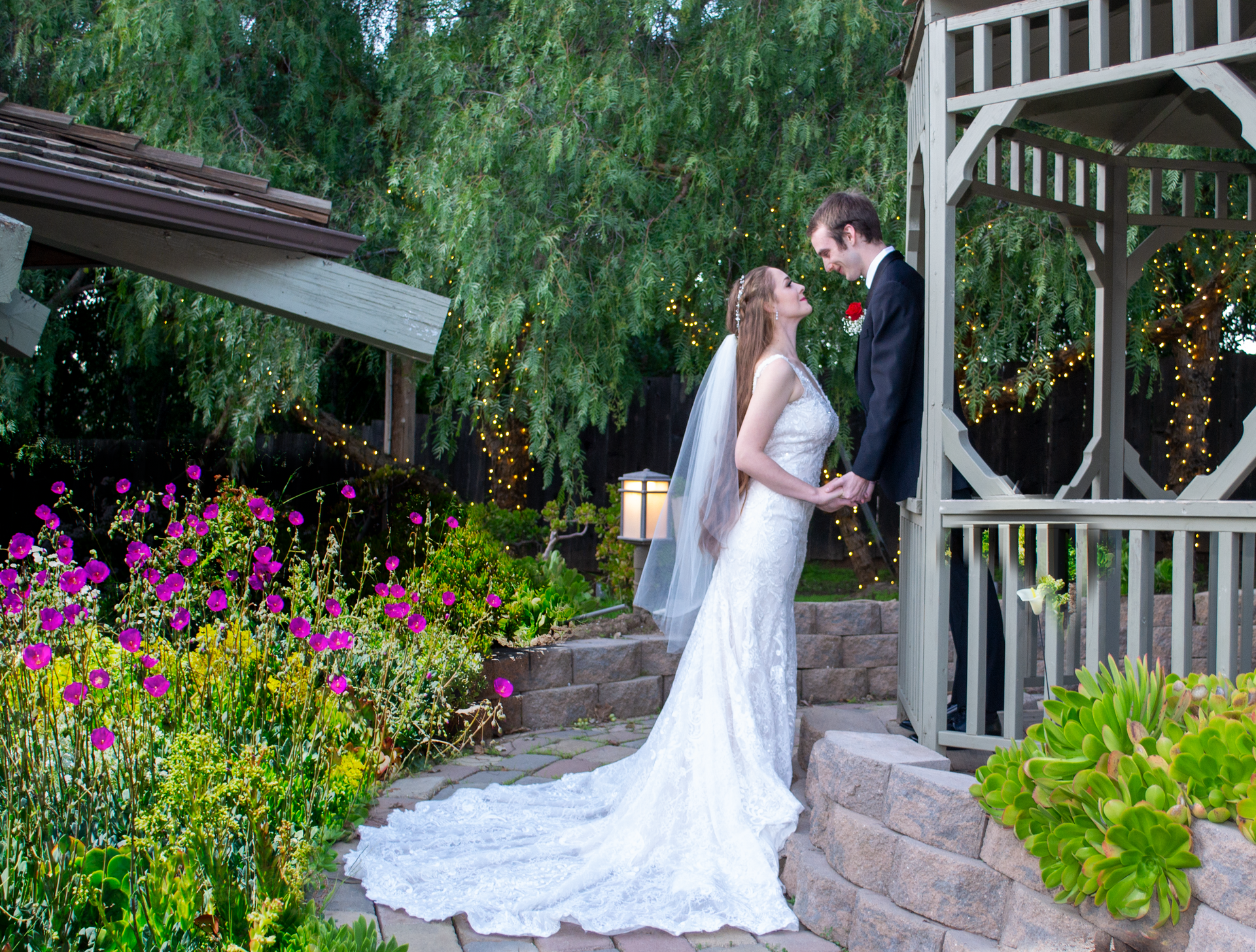 A bride and groom are posing for a picture in front of a gazebo.