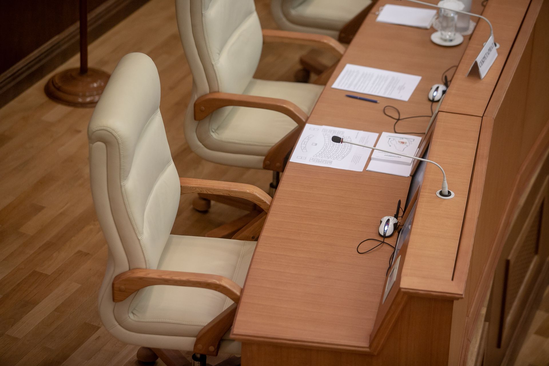 A row of empty chairs are sitting at a long wooden table.