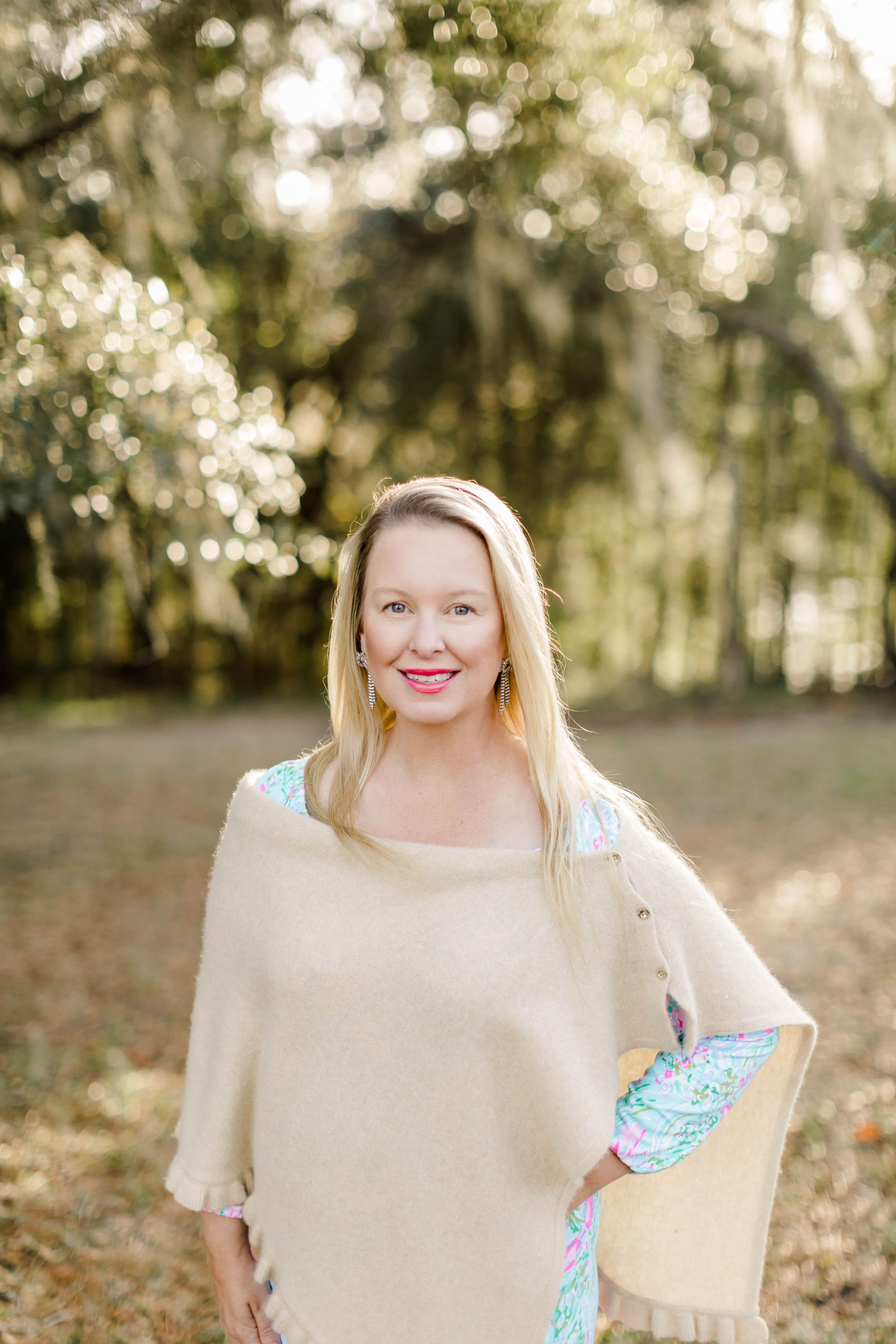 A woman is standing in a field wearing a poncho.