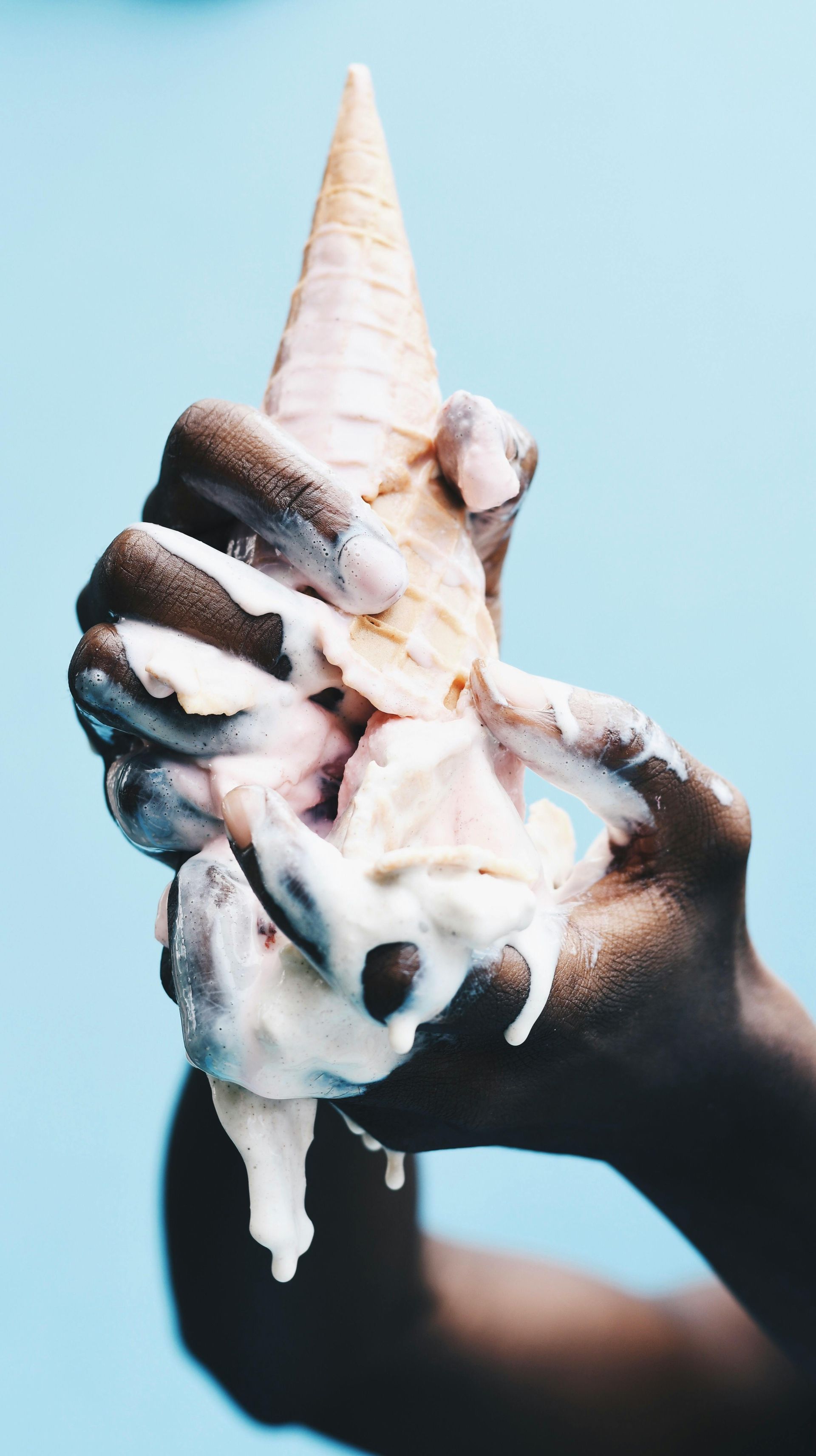 A person is holding a melted ice cream cone in their hand.