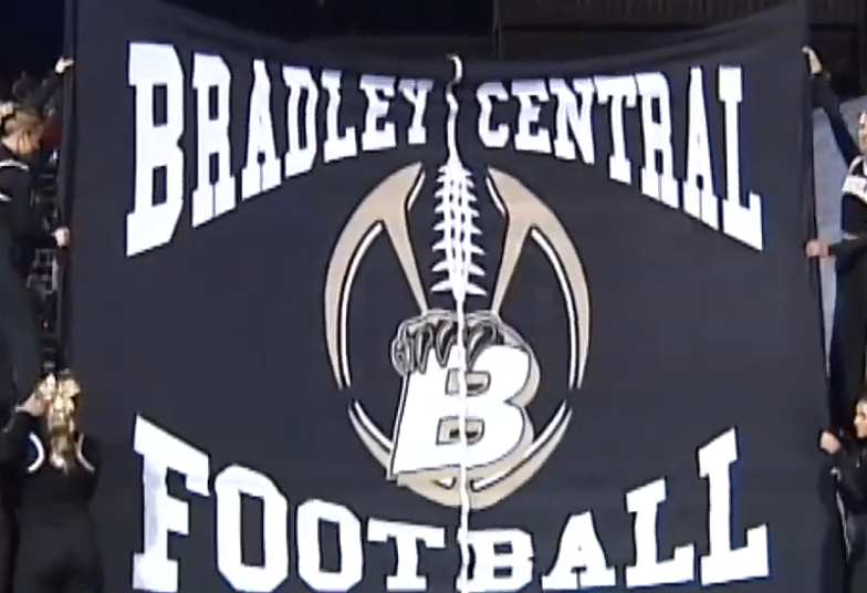 A banner held by cheerleaders reads 
