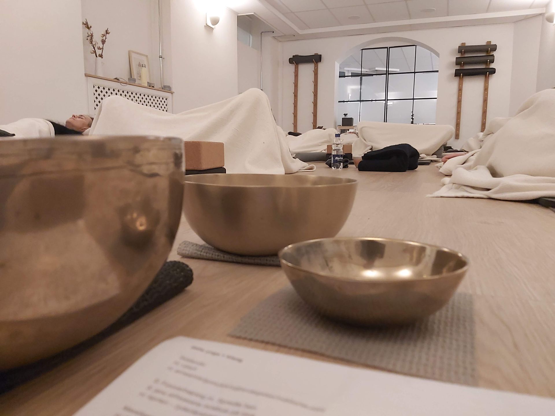 En person ligger på en seng i et værelse med skåle på gulvet