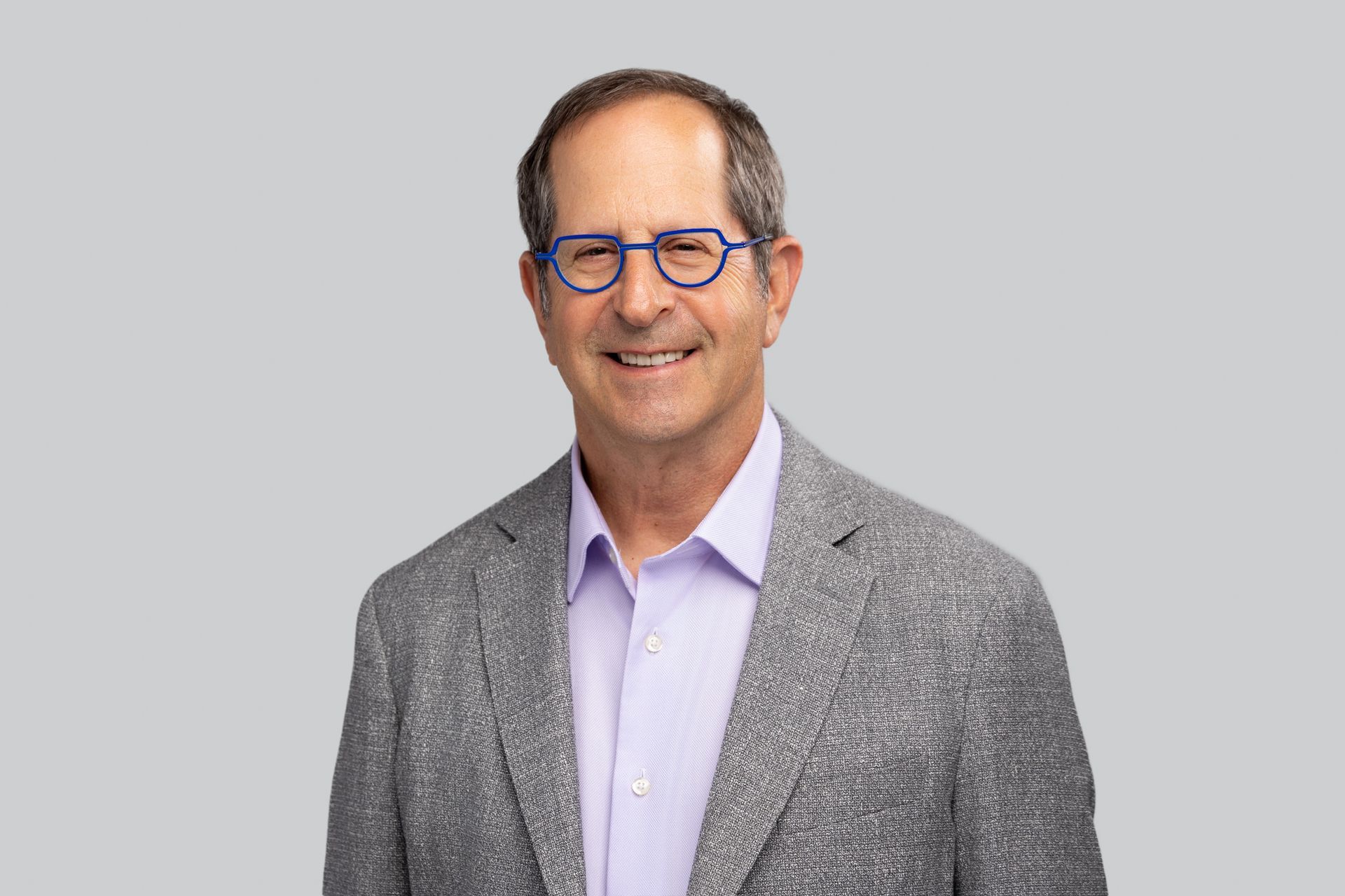 A man in a suit and glasses is smiling for the camera.