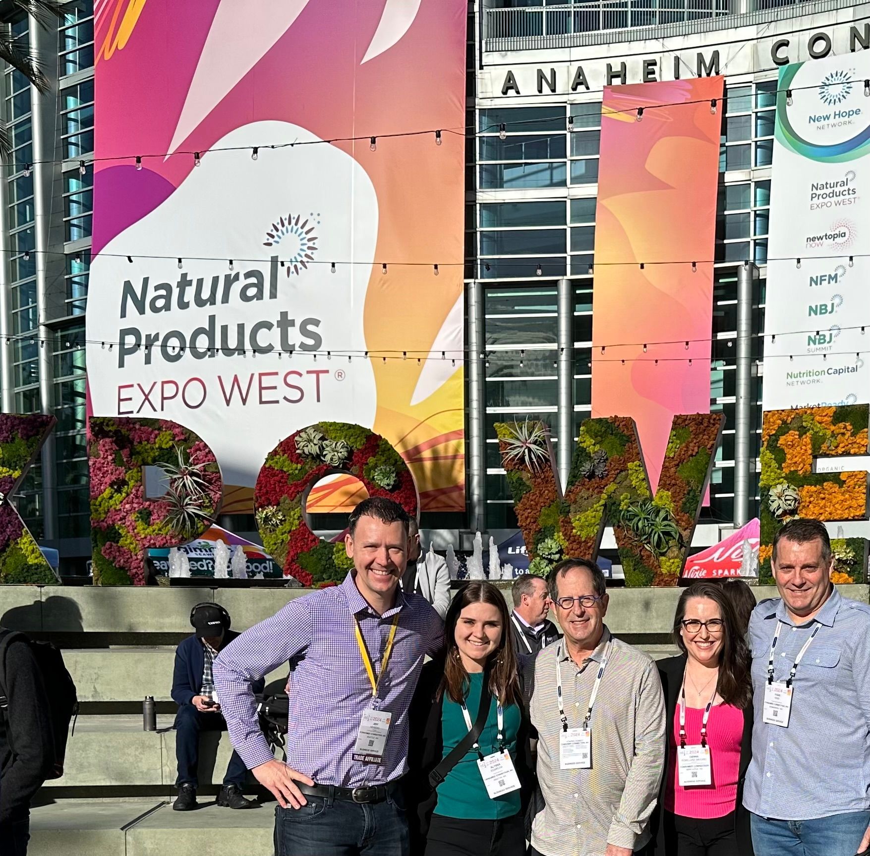 A group of people standing in front of a sign that says natural products expo west