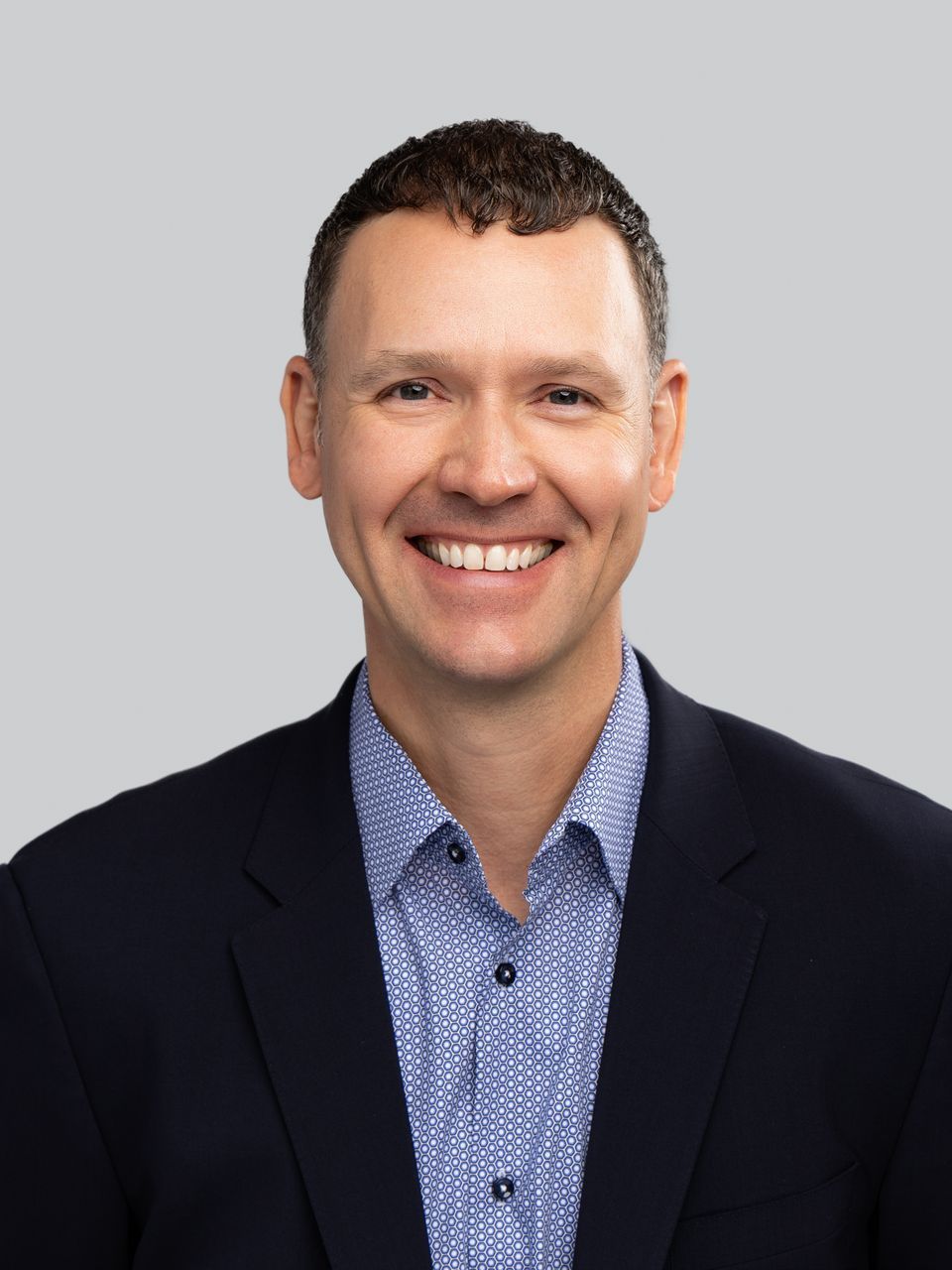 A man in a suit and blue shirt is smiling for the camera.