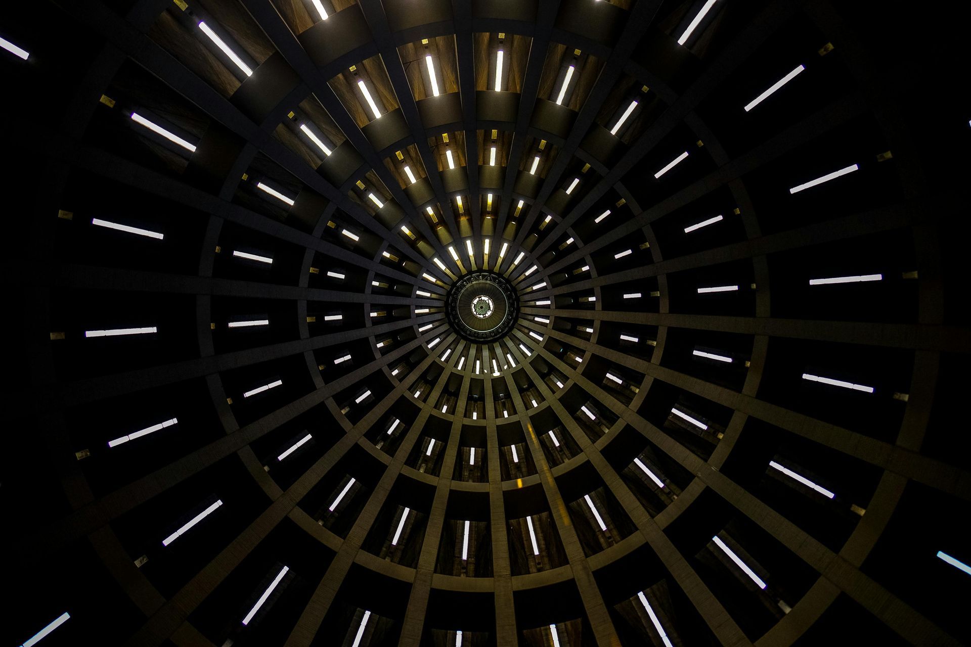 Looking up, circular interior with radiating lines of bright lights, dark background.