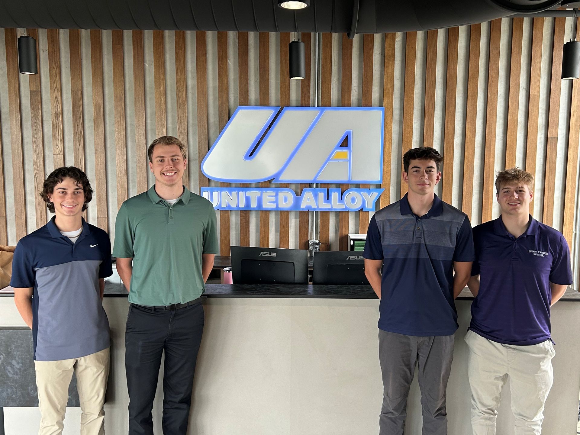 Smiling United Alloy college interns at the front desk.
