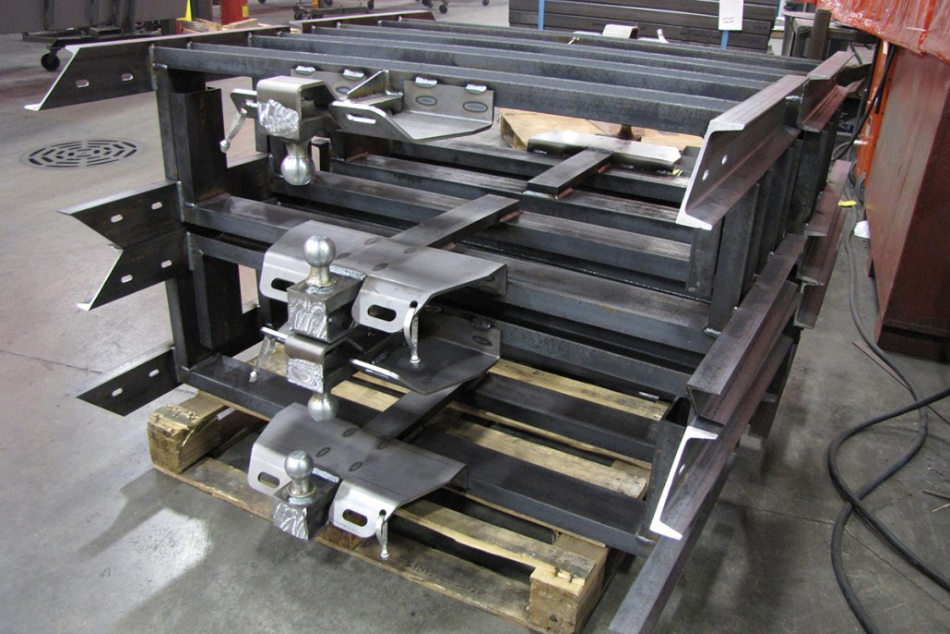 Inventory of heavy-duty trailer tongue assemblies featuring integrated pintle hitches and safety chains.