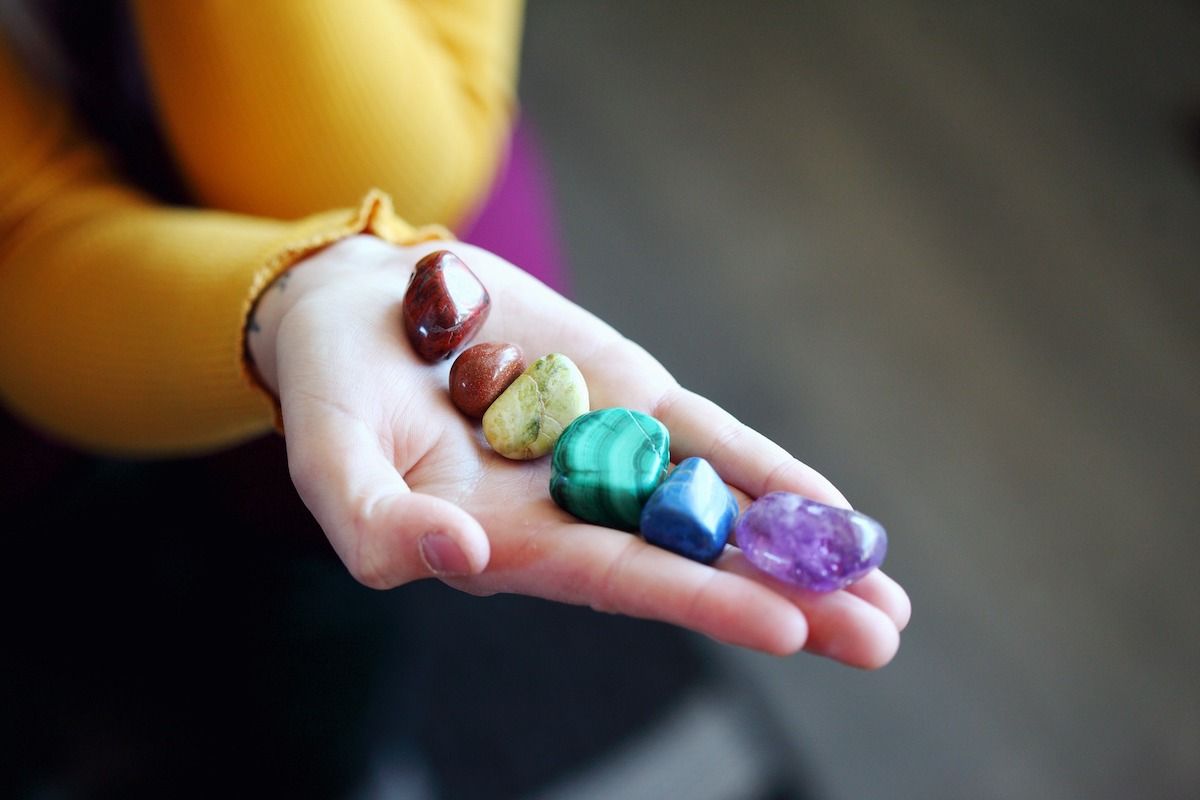 A person is holding a handful of rainbow colored crystals.