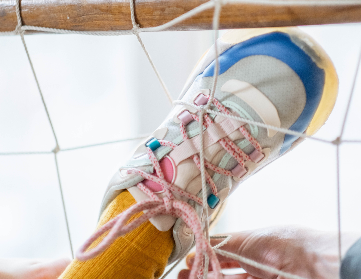 A person is tying a shoe with a string