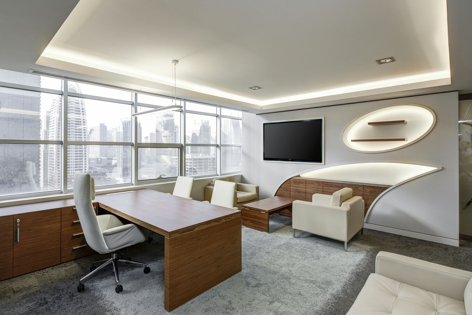 A modern office with a large table , chairs , and a flat screen tv.