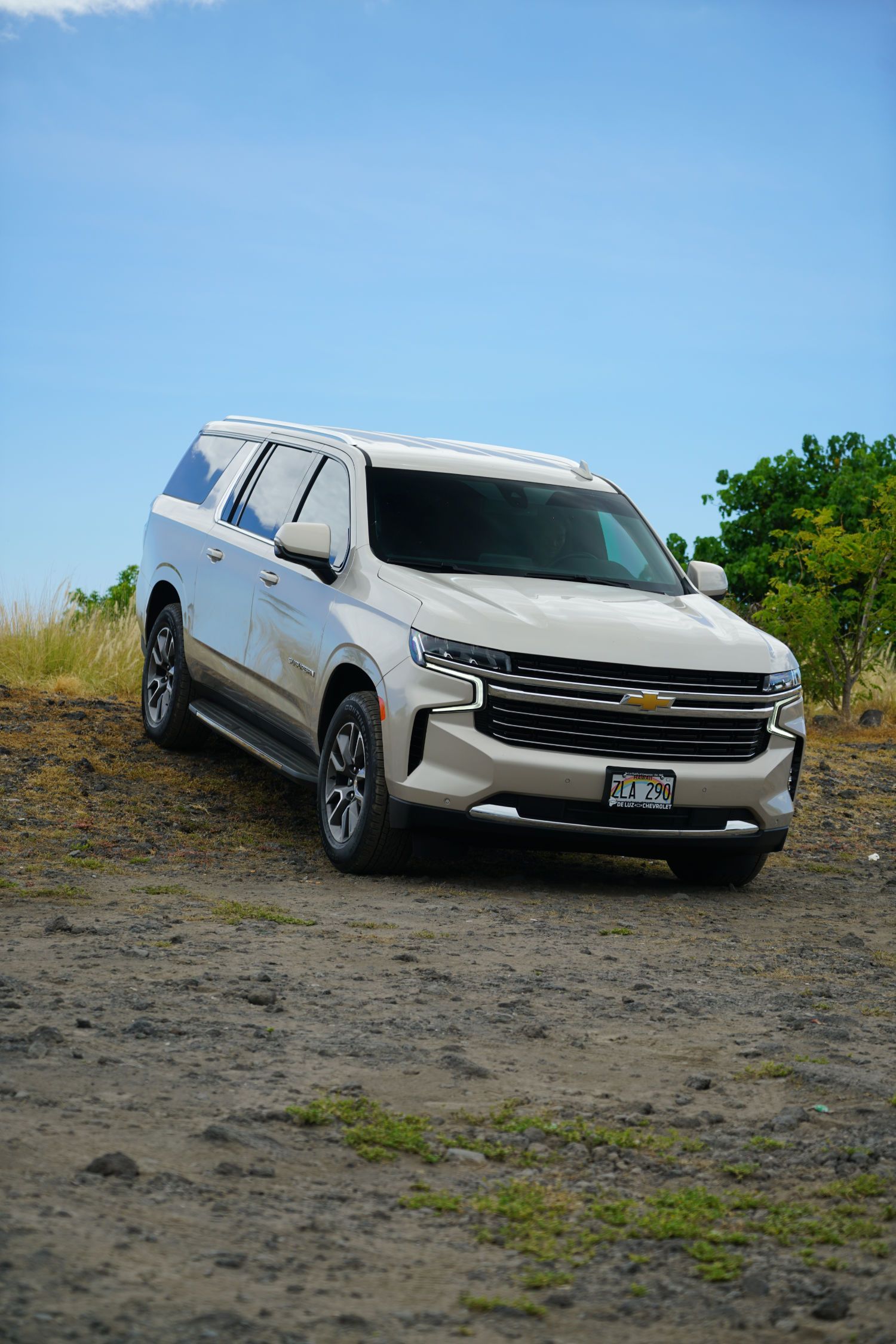 A white suv is parked on top of a dirt hill.