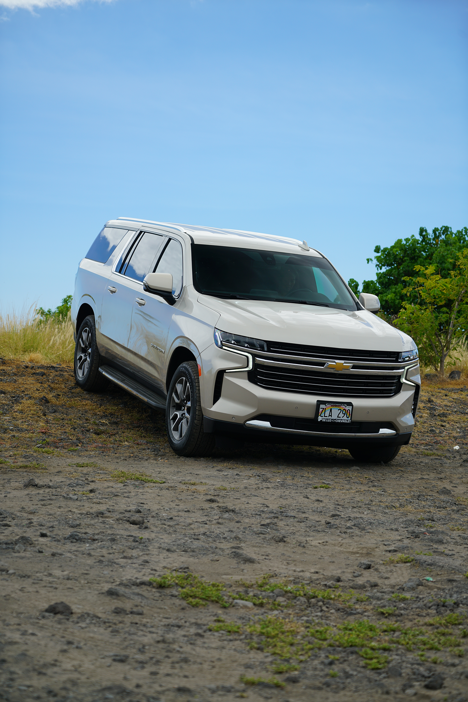 A white suv is parked in a dirt field.