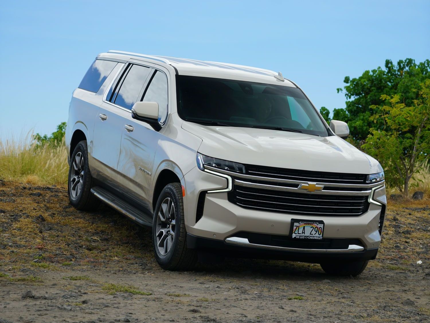 A white suv is parked in a dirt field.