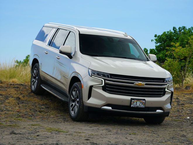 A white suv is parked in a dirt field.