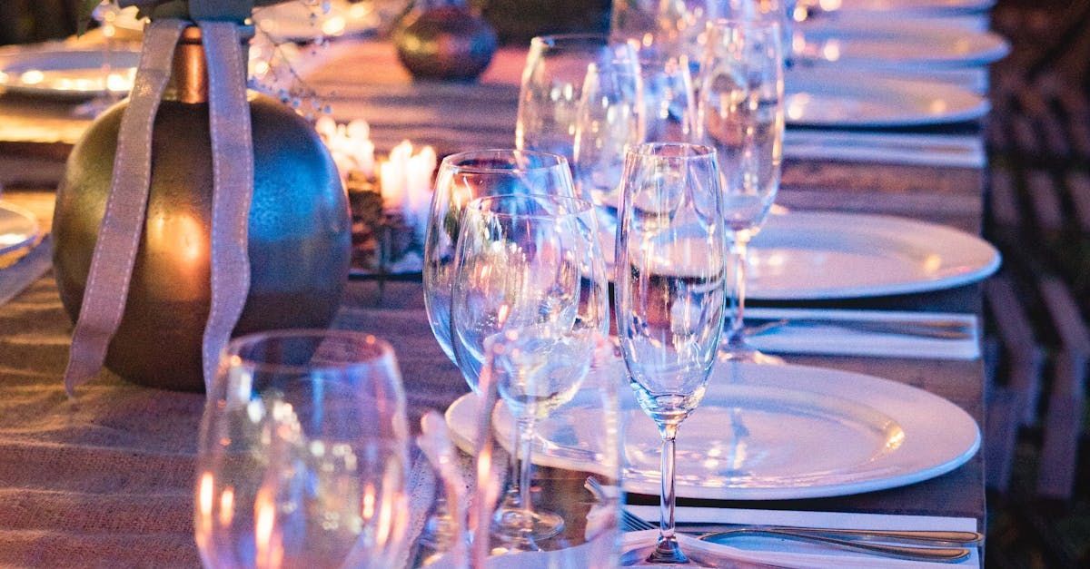 A long table with plates , wine glasses , and candles on it.