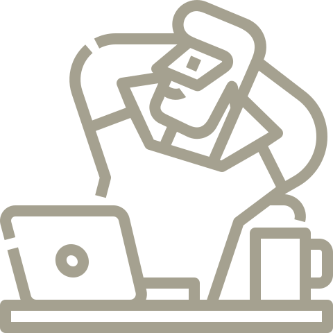 A man is sitting at a desk with a laptop and a cup of coffee.
