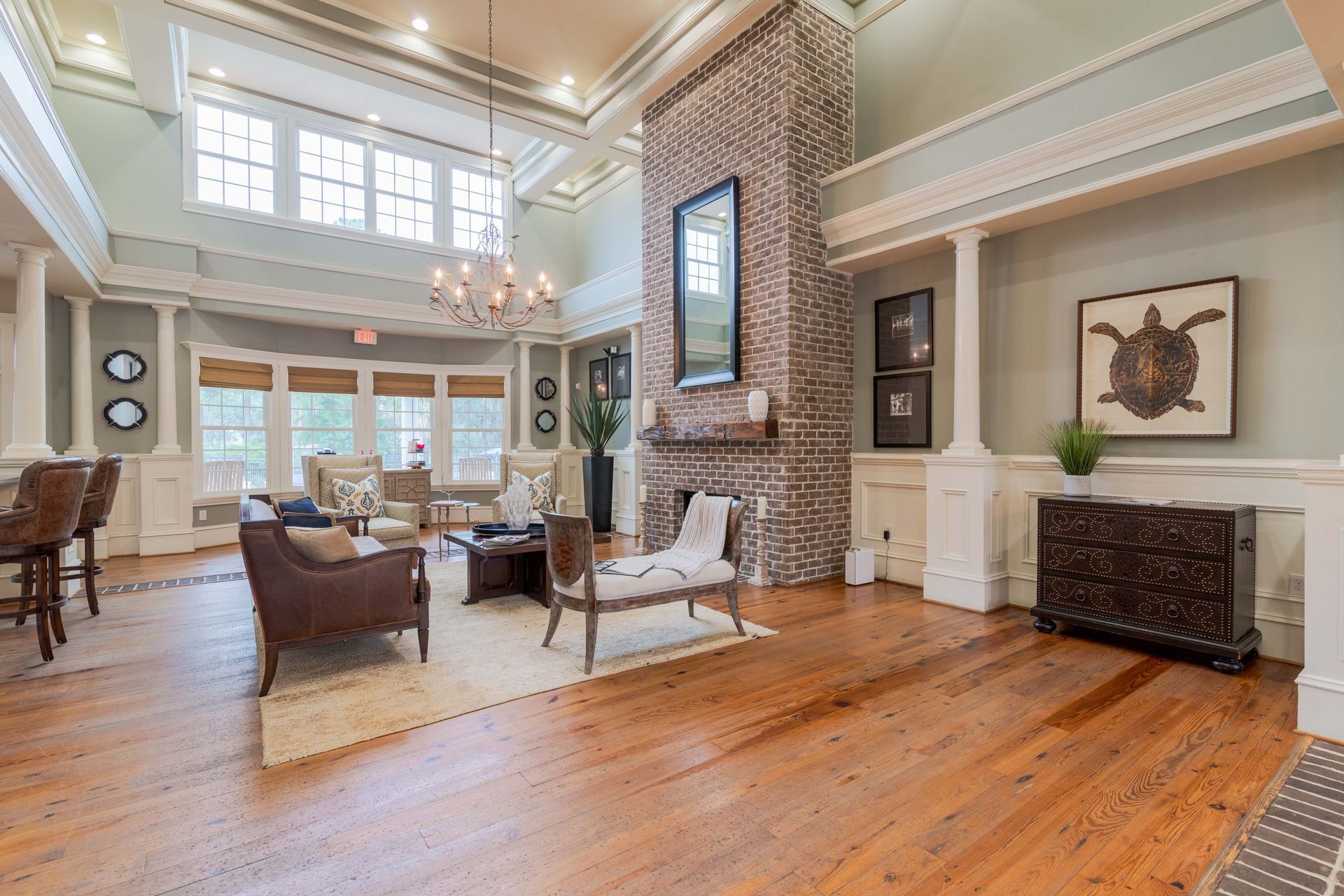 Spacious living area with wooden floor, brick fireplace, and furniture. Pastel walls and decorative molding at Grand Oaks at Ogeechee River in Savannah, GA.