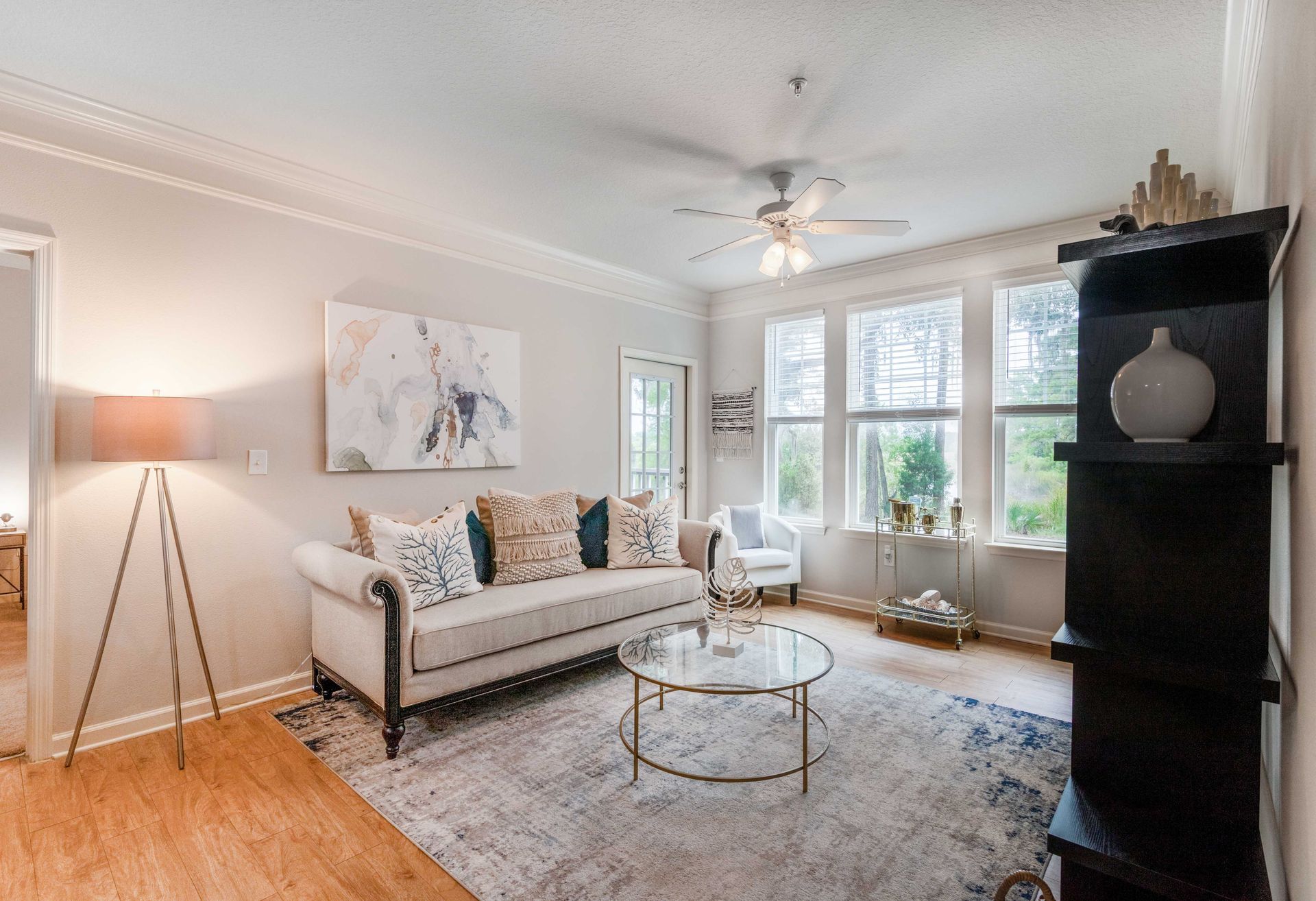 Living room with sofa, coffee table, rug, artwork, and windows at Grand Oaks at Ogeechee River in Savannah, GA.