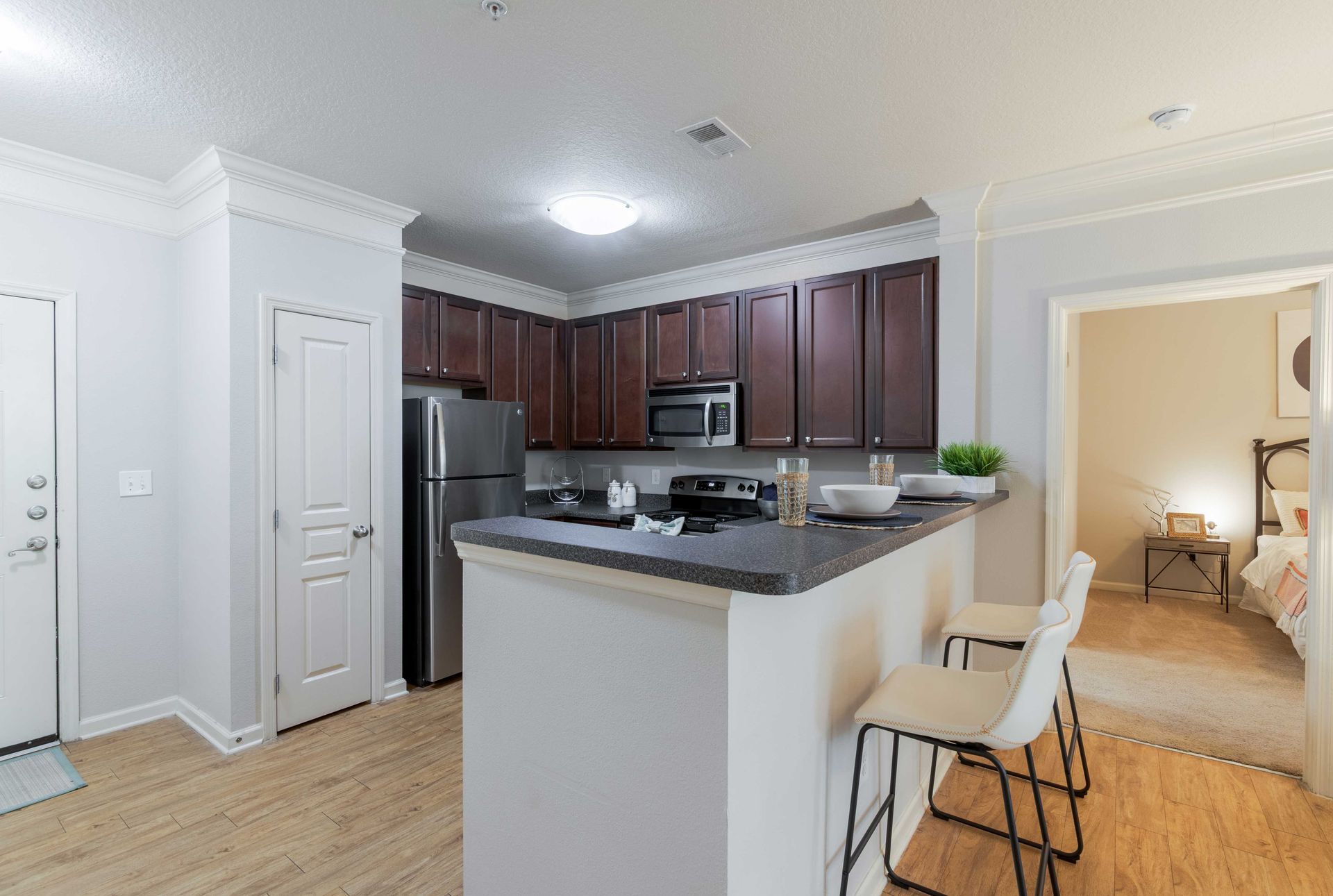 Kitchen with dark cabinets, stainless steel appliances, breakfast bar, and doorway to a bedroom at Grand Oaks at Ogeechee River in Savannah, GA.