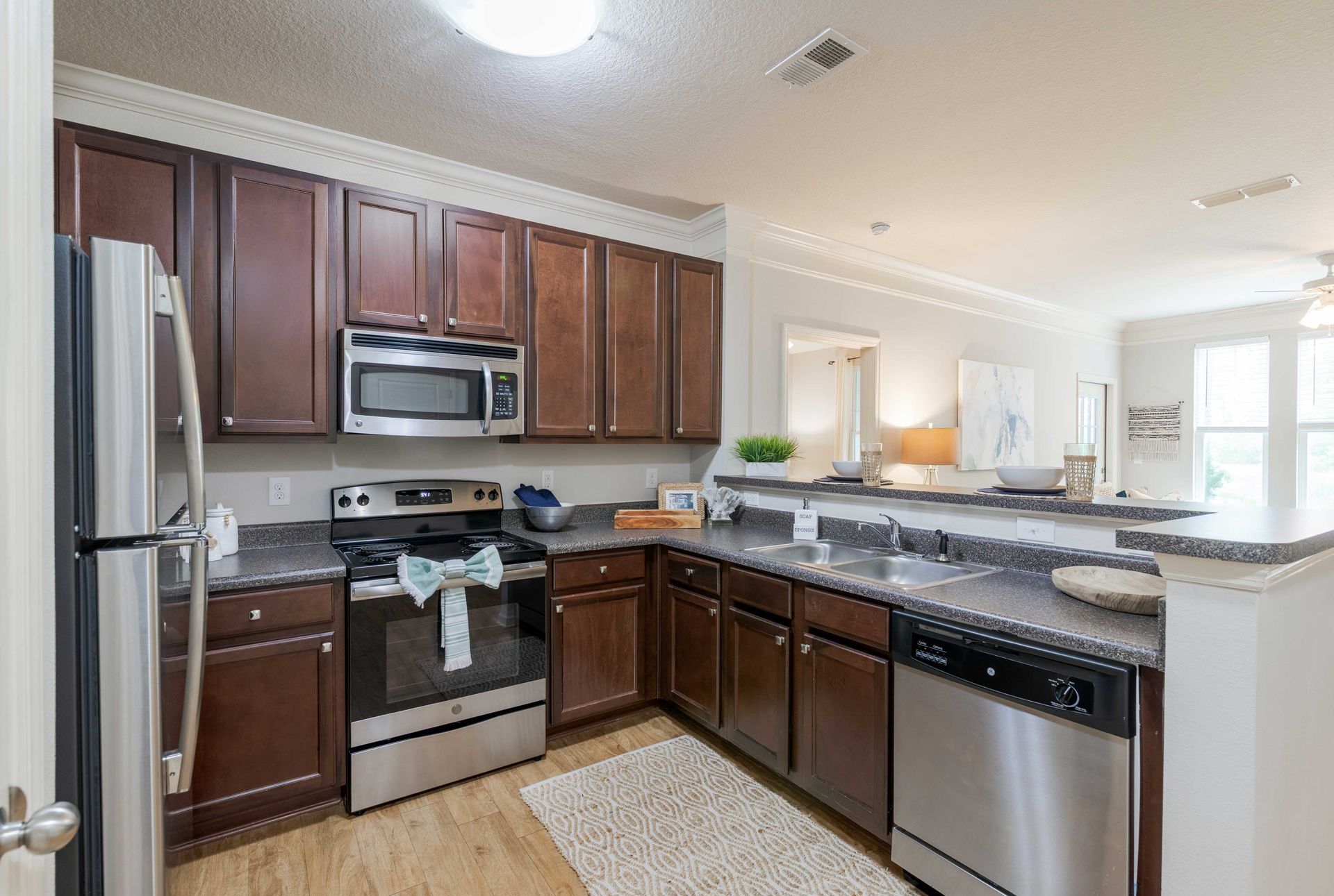 Kitchen with brown cabinets, stainless steel appliances, and gray countertops at Grand Oaks at Ogeechee River in Savannah, GA.