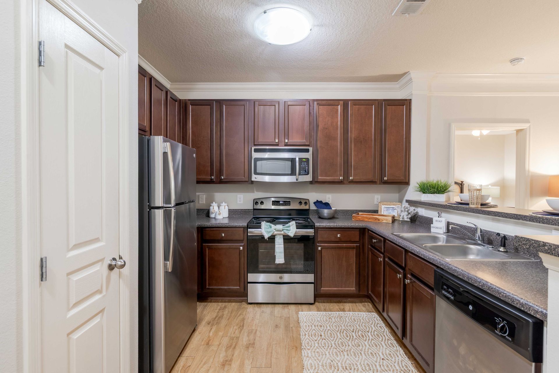 Kitchen with dark brown cabinets, stainless steel appliances, and a light-colored floor at Grand Oaks at Ogeechee River in Savannah, GA.