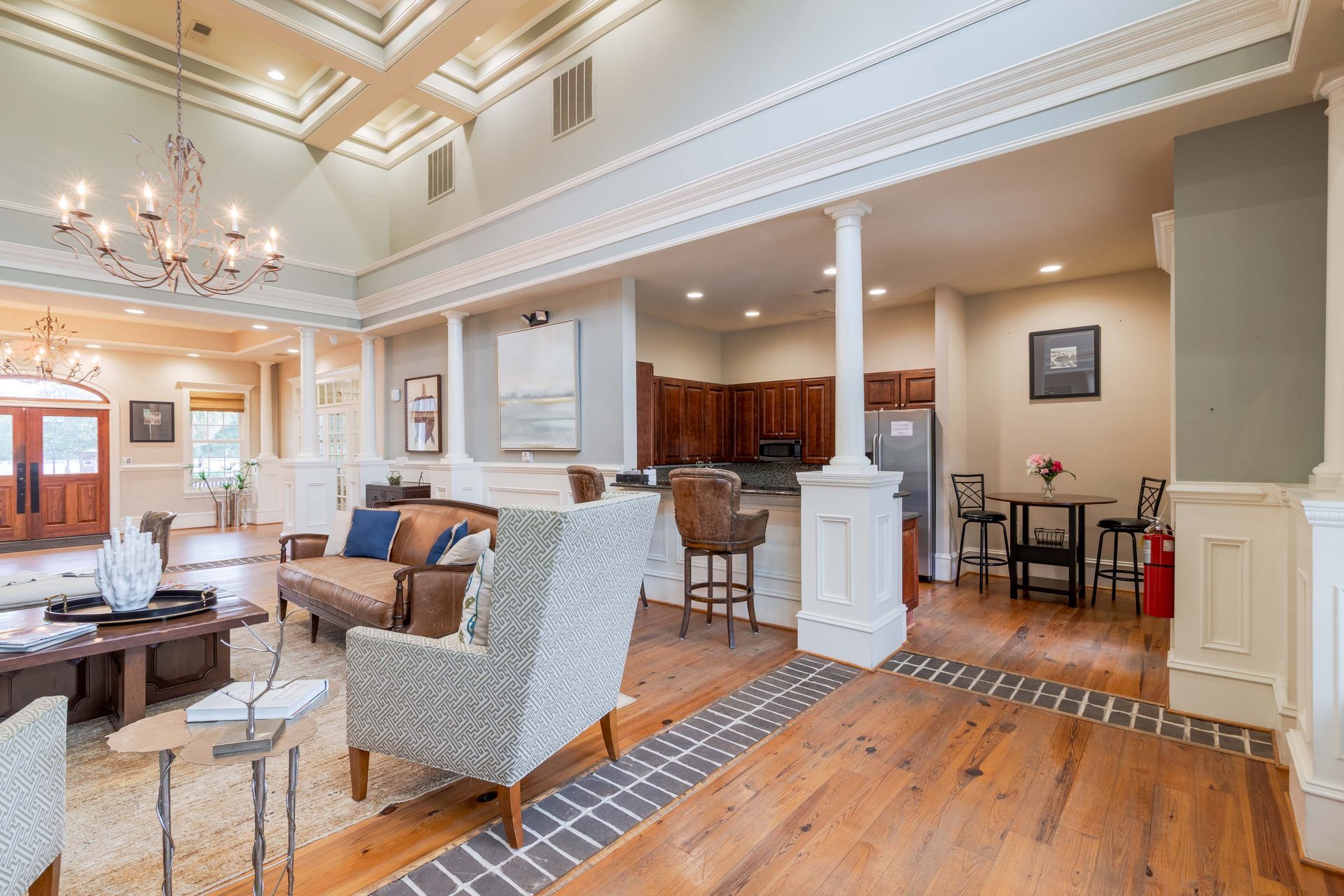 Elegant open-concept clubhouse with columns, wood floors, seating, and a small kitchen area at Grand Oaks at Ogeechee River in Savannah, GA.