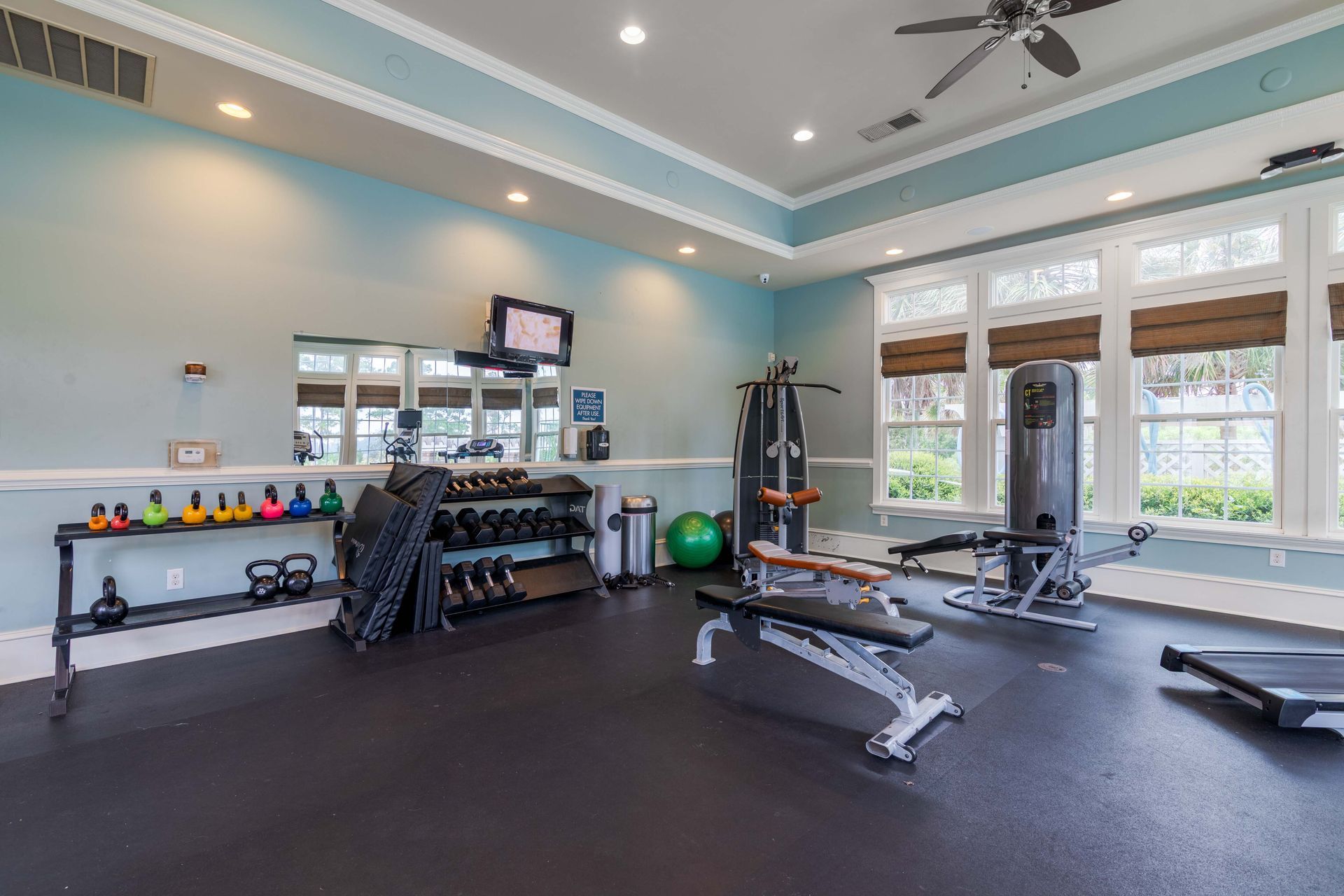 Gym with exercise equipment, including weights, a multi-gym, and a bench, with windows at Grand Oaks at Ogeechee River in Savannah, GA.