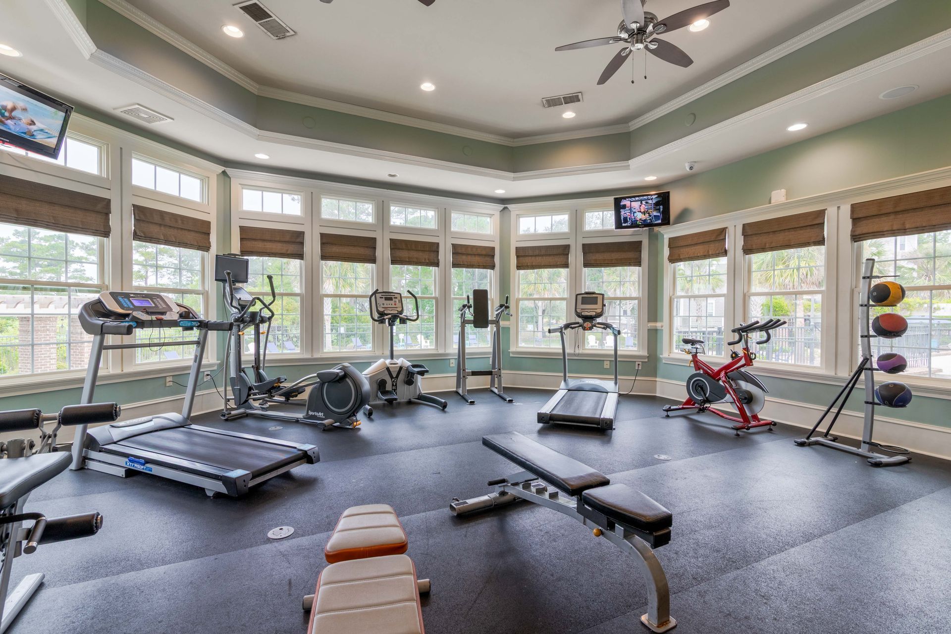 Gym with treadmills, elliptical, exercise bike, weights, and large windows at Grand Oaks at Ogeechee River in Savannah, GA.