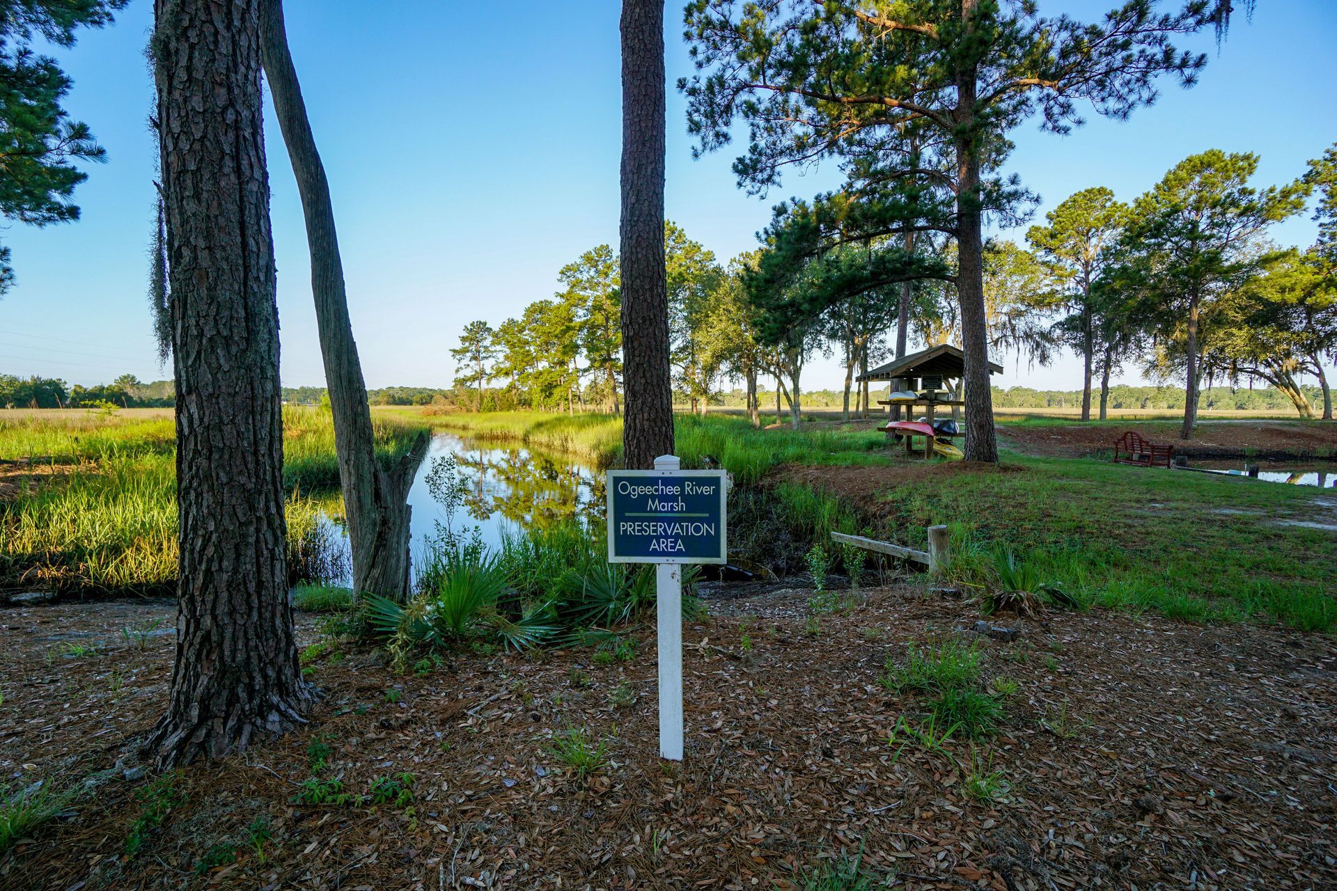 Sign in a wooded park by a pond, with trees and a gazebo in the background at Grand Oaks at Ogeechee River in GA