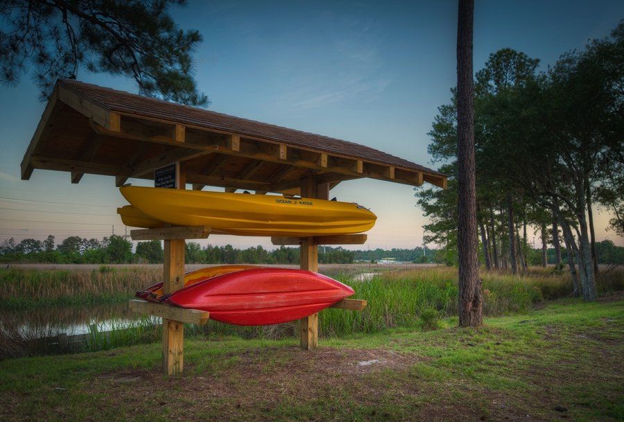 Three kayaks are stacked on top of each other under a wooden structure at Grand Oaks at Ogeechee River, offers pet-friendly apartments for rent in Savannah, GA.