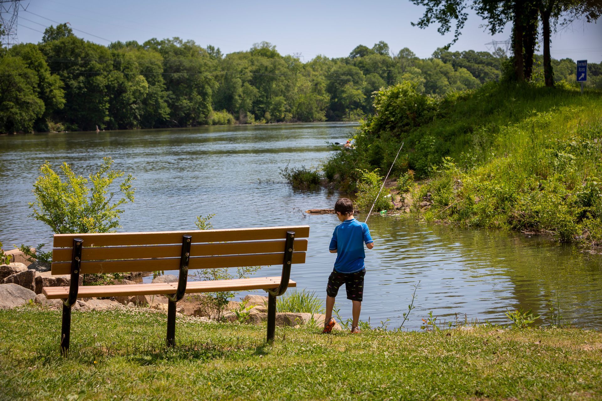 A boy is sitting on a bench looking at a lake at Grand Oaks at Ogeechee River in GA